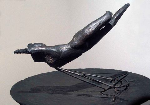 Sculpture. A bronze object like a diving bird or falling person is supported by a cantilevered wire base.