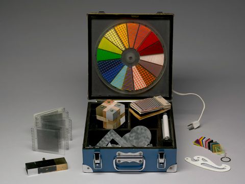 Sculpture. A blue case holds samples of materials and a neon light in compartments in the bottom. A Plexiglas wheel with slices of colour and pattern is mounted to the open lid like a turntable. Other materials from the sample box are displayed around it.